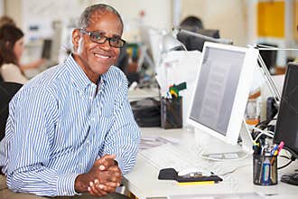 Man Working At Desk In Busy Creative Office