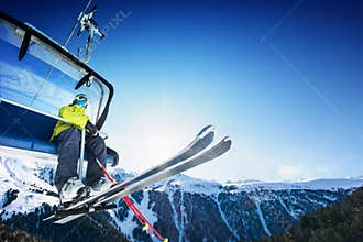 Skier siting on ski-lift - lift at sunny day and mountain
