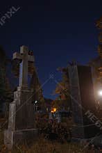 Night cemetery tomb stone and cross gothic style Halloween season time vertical photography with glare of light effect and vibrant