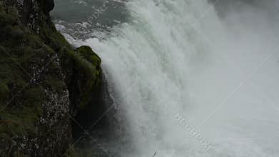 Close up of waterfall pouring over black cave entrance