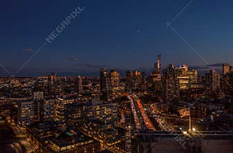 Aerial view of city after sunset. Town development and busy transport infrastructure in urban neighbourhood. Night city