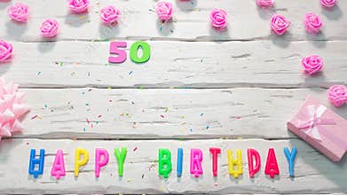 Top view of happy birthday 50 candle letters for a girl in pink shades with beautiful rose flowers, postcard congratulation copy