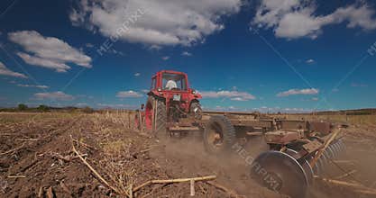 Tractor cultivating fields. Tractor harrowing the ground in a agricultural field. Cultivate, agriculture and farming concept.