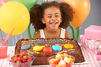 Young girl with birthday cake and gifts at party