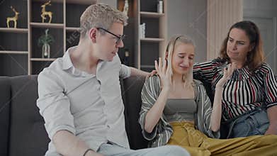 Worried mom and dad comforting depressed teen daughter bonding at home. Fam loving understanding and supporting sad teenage girl