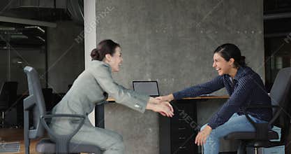 Businesswomen have fun riding seated on chairs at workplace