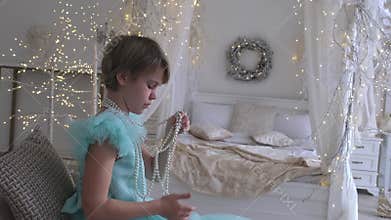 A beautiful teenage girl in a chic dress with an open back. A girl looks with interest at a Christmas present - a string