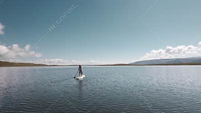 Girl walks on sup paddle board mountain lake