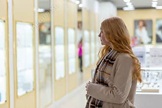 Young woman looking at the shop showcase and jewelry to look at it closer