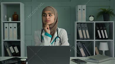 Thoughtful sad bored young therapist doctor woman sitting at clinic alone worried unmotivated lazy female physician