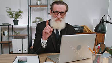 Business man working on laptop shakes finger, saying no, be careful, giving advice to avoid mistake