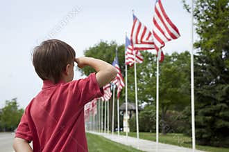 Young boy saluting American flags on Memorial Day
