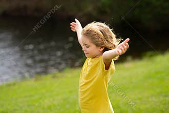 Child faith, praise and happiness and freedom. Kid resting in summer park. Kid put face to the sun, closed her eyes and