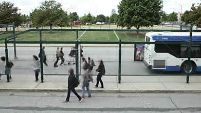 People boarding a city bus at a busy transit stop on a cloudy day
