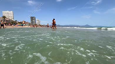 Alicante, Spain - May 18, 2025: Relaxing beach day with families and friends enjoying the sun and surf at a coastal