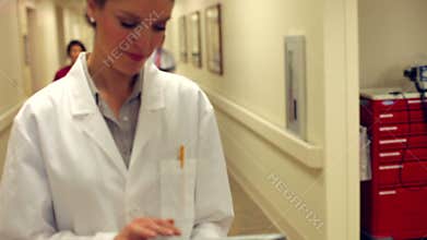 Doctor Walking Along Hospital Corridor Using Digital Tablet
