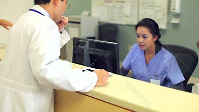 Doctor Walking Along Hospital Corridor Using Digital Tablet