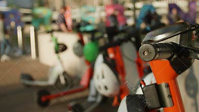 Closeup footage of Electric scooters parked in a row on a sunny day in parkland