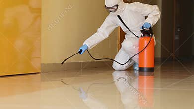 Pest control worker wearing protective suit sprays disinfectant