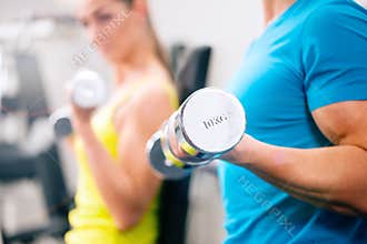 Couple training for fitness in gym with weights