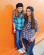 Stylish mother and child daughter together, happy mom with kid girl in casual clothing in the city