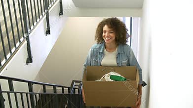 Woman Moving Into New Home Carrying Box Upstairs