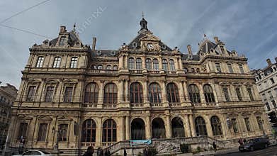 Palais de la Bourse in Lyon, France with pedestrians in the front street under cloudy sky