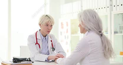 Doctor calms patient during consultation holding woman hands