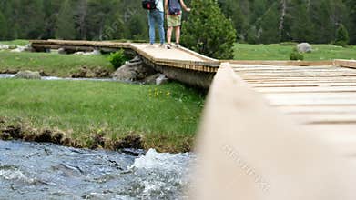 Blurred View of Tourists are Passing through Winding Wooden Bridge-trail over Mountain Streams.