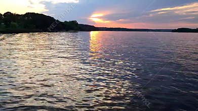 Quiet sunset on the lake with reflection in the water and forest shore.