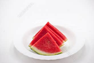 Freshly sliced watermelon pieces arranged neatly on a white plate ready to be enjoyed during a summer gathering