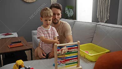 Father and son playing with an abacus together in a cozy living room