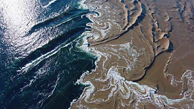 aerial view of ocean waves meeting desert sand, captivating natural phenomenon. earth patterns and contrasts concept