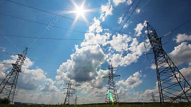 tall electric masts against sun and cloudy sky - timelapse