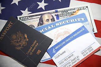 American passport with health insurance and social security card placed along the 100 dollars bill on American flag in the