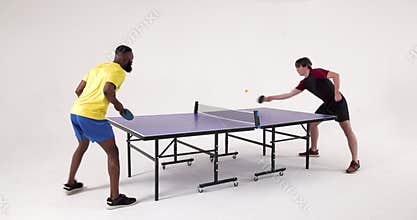 Playing table tennis, two men competing in fast-paced match indoors