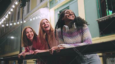 Three Women Engaging in Enjoyable Evening Conversations on a Vibrant and Colorful Balcony, Surrounded by the Charming