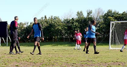 Playing soccer on field, teams in blue and red jerseys competing actively