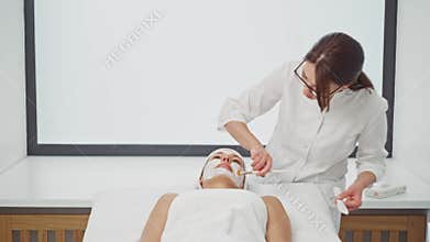 Butikan applies anesthesia to the skin of the woman's face.