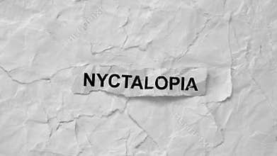 Crumpled piece of paper with word Nyctalopia on torn white paper pieces background.