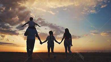 Silhouette of a family with big children. Park aquarium zoo concept. A family of four walking at sunset. Silhouette of a