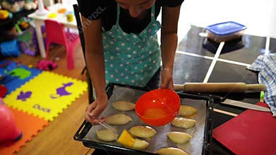 Woman smears pies on a baking sheet with a beaten egg with a brush