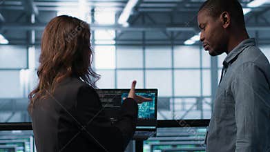 Programmers coding on laptop using artificial intelligence in server farm