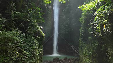 Drone shoot. Waterfall hidden in tropical rainforest jungle, falling water hitting water surface, some huge rocks