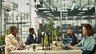 Accountant in busy modern startup agency imputing financial figures on PC