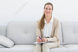 Smiling female psychologist sitting on sofa