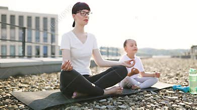 Adult and child practicing meditation together outside on sunny day
