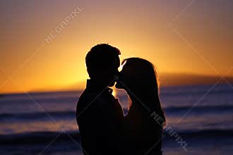 Silhouette of a young couple kissing at the beach