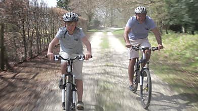 Father And Son Riding Bikes Along Country Track