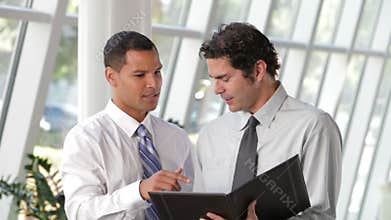 Two Businessmen Discussing Document In Office
